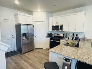 Kitchen with appliances with stainless steel finishes, light granite countertops, white cabinets, and recessed lighting