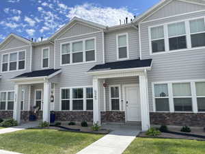 View of property featuring stone siding and a front lawn