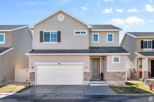 View of front of home with stone siding, stucco siding, and concrete driveway