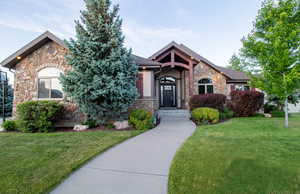 View of front of home featuring stone siding, a front lawn, and a shingled roof