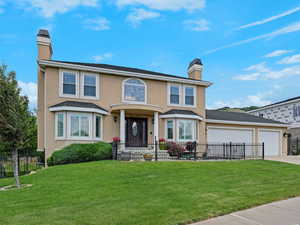 Traditional home with a chimney, an attached garage, driveway, and stucco siding