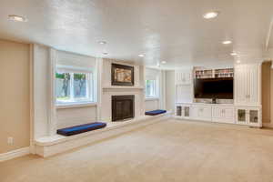 Living room featuring light colored carpet, a fireplace, healthy amount of natural light, recessed lighting, and a textured ceiling