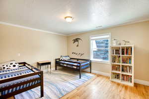 3rd Bedroom featuring wood finished floors, ornamental molding, and a textured ceiling