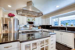 Kitchen featuring appliances with stainless steel finishes, island range hood, white cabinetry, crown molding, and tasteful backsplash