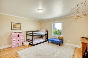 2nd Bedroom featuring crown molding, wood finished floors, and a textured ceiling