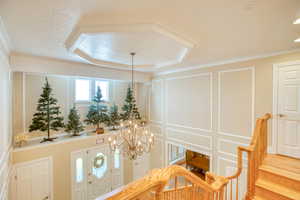 Entryway featuring a decorative wall, a chandelier, and ornamental molding
