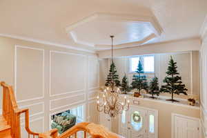Foyer with a decorative wall, a chandelier, and crown molding