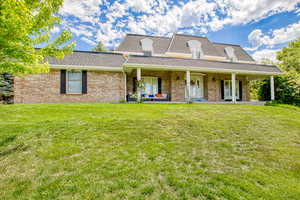 View of property featuring a front yard, a shingled roof, and brick siding