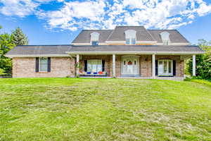 View of front facade featuring an outdoor hangout area, a front yard, brick siding, and roof with shingles