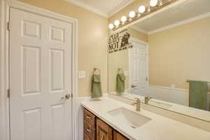 Bathroom featuring vanity, wainscoting, and crown molding