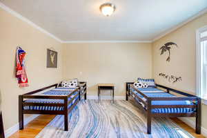 3rd Bedroom with a textured ceiling, crown molding, and wood finished floors