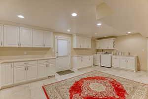 Washroom featuring separate washer and dryer, cabinet space, and recessed lighting