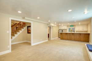 Living room featuring recessed lighting, light carpet, and stairs