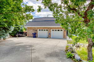 View of side of property featuring concrete driveway, a garage, and brick siding