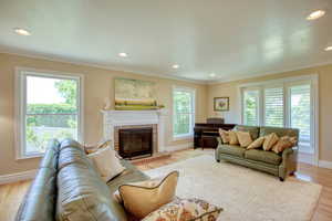 Living area featuring plenty of natural light, a fireplace, crown molding, recessed lighting, and light wood-type flooring