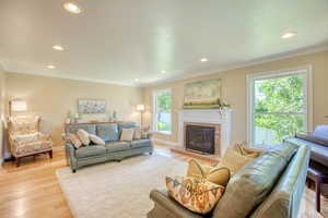 Living room with recessed lighting, light wood-style flooring, a fireplace, and ornamental molding