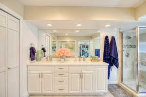 Full bathroom featuring a closet, double vanity, a shower stall, recessed lighting, and tile patterned flooring