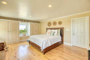 Primary bedroom featuring light wood-style floors, ornamental molding, and recessed lighting
