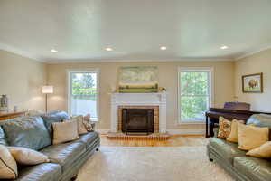 Living room with healthy amount of natural light, light wood finished floors, recessed lighting, a fireplace, and ornamental molding