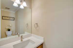 Bathroom with crown molding, vanity, and a chandelier