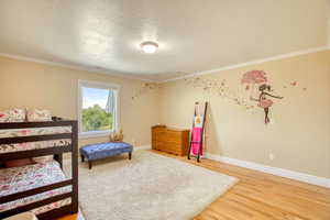 2nd Bedroom with ornamental molding, a textured ceiling, and light wood-style flooring