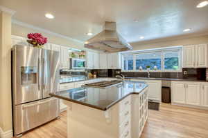Kitchen with stainless steel appliances, island range hood, light wood-type flooring, healthy amount of natural light, and recessed lighting