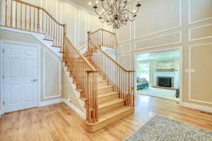 Stairway with a decorative wall, wood finished floors, a chandelier, and a fireplace