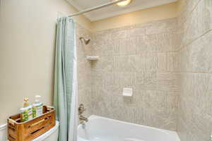Bathroom with shower / tub combo and ornamental molding