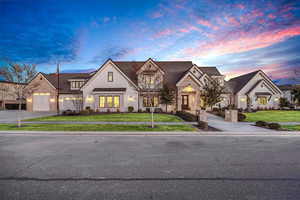 French country inspired facade with stone siding and a front yard