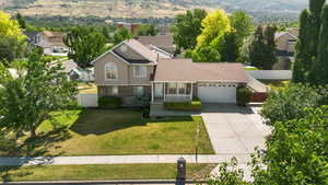 View of front of home with driveway, a garage, brick siding, a mountain view, and a porch