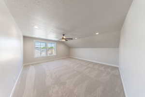 Additional living space featuring a textured ceiling, ceiling fan, light carpet, vaulted ceiling, and recessed lighting