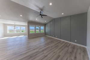 Unfurnished room with a textured ceiling, a decorative wall, ceiling fan, light wood finished floors, and a chandelier