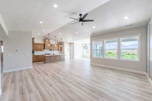 Unfurnished living room with vaulted ceiling, ceiling fan, light wood-type flooring, recessed lighting, and a textured ceiling