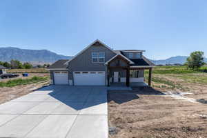 View of front of home featuring a mountain view, driveway, board and batten siding, covered porch, and a garage