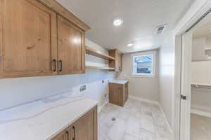 Laundry area with cabinet space,  hookup for a washing machine, a textured ceiling, and recessed lighting