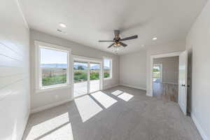 Empty room featuring light carpet, healthy amount of natural light, ceiling fan, and recessed lighting
