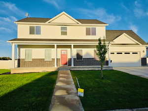 View of front of property featuring covered porch, brick siding, driveway, and a garage