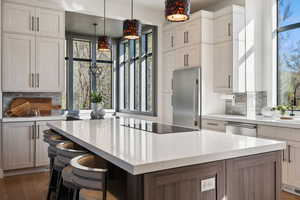 Kitchen featuring appliances with stainless steel finishes, plenty of natural light, light countertops, and backsplash