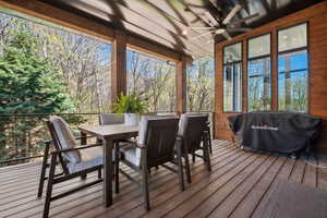 Wooden terrace featuring ceiling fan, outdoor dining space, and area for grilling