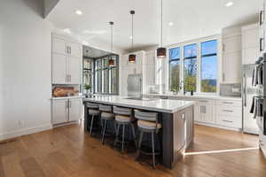 Kitchen with built in fridge, backsplash, recessed lighting, an island with sink, and light wood-style floors