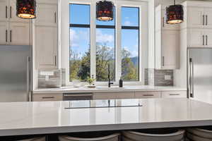 Kitchen with high quality fridge, built in refrigerator, backsplash, and hanging light fixtures