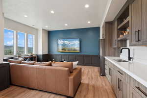 Living room with recessed lighting, light wood finished floors, a wainscoted wall, and a decorative wall
