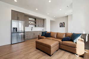 Living room featuring bar with sink, light wood-type flooring, and recessed lighting