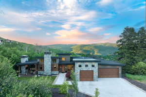 Contemporary house featuring stone siding, a garage, a standing seam roof, and concrete driveway