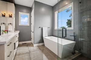 Full bath with double vanity, a freestanding tub, and a shower with shower door