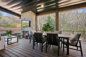 Wooden deck with an outdoor stone fireplace and outdoor dining area