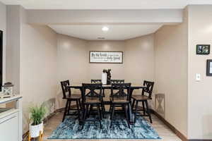 Dining room with light wood finished floors and recessed lighting