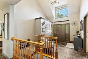 Entryway featuring stone tile floors, a chandelier, and high vaulted ceiling