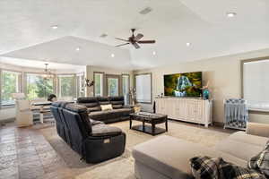 Living room featuring lofted ceiling, recessed lighting, a ceiling fan, and stone tile floors