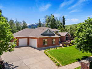 View of front of house with an attached garage, a front lawn, brick siding, concrete driveway, and roof with shingles